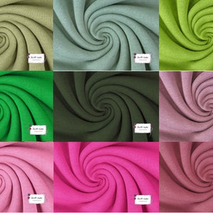 May include: A collection of nine fabric swatches in various colors, including green, pink, and brown. Each swatch is rolled into a spiral shape, showcasing the texture of the fabric.
