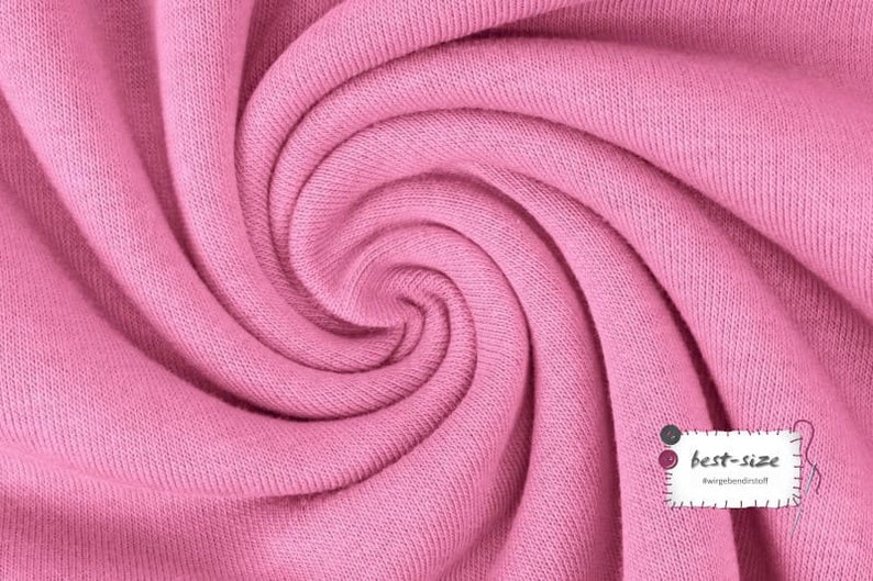 May include: Close-up of a soft, pink fabric with a textured surface. The fabric is folded and twisted, creating a swirling pattern.