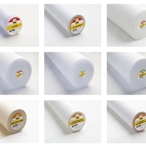 Könnte beinhalten: Neun Rollen weißer und cremefarbener Einlage. Die Etiketten auf den Rollen enthalten den Text "H 200", "H 250/300", "DECOVIL LIGHT", "STICK & STITCH", "STICK & STITCH" und "STICK & STITCH".