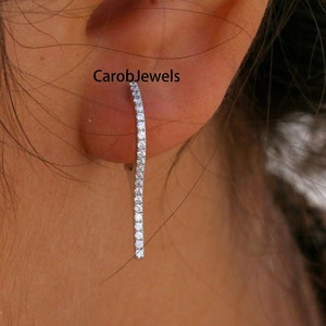 May include: A pair of long, thin, diamond-encrusted earrings. The earrings are made of white gold and have a simple, elegant design.