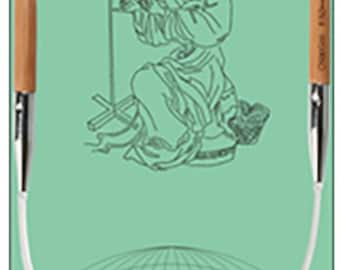 May include: A pair of circular knitting needles with wooden tips and a silver cable. The needles are shown against a green background with a drawing of a woman spinning yarn.