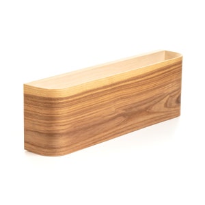 May include: A wooden wall shelf with a curved front edge. The shelf is made of light brown wood with a natural wood grain pattern.