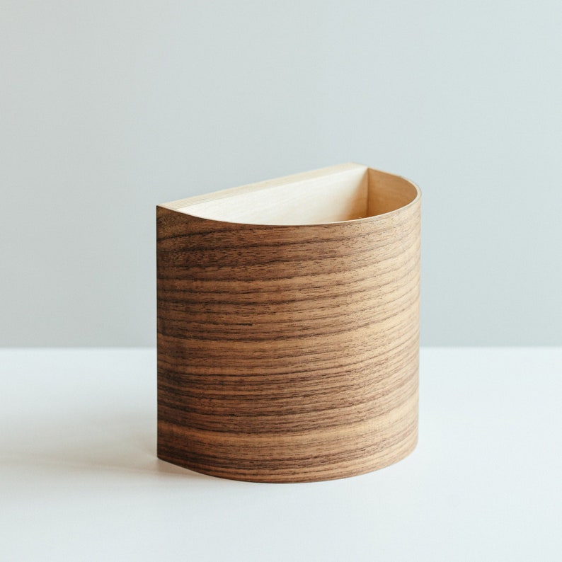 Puede incluir: Un organizador de pared de madera semicircular con un acabado de veta de madera natural.