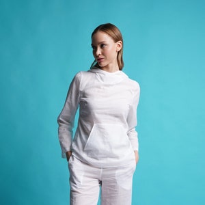 May include: A white hooded sweatshirt and matching pants. The model is wearing the outfit and standing on a light blue background.