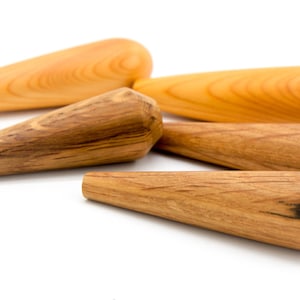 May include: Five wooden dowels, some with a natural finish and others with a darker wood grain, are arranged in a staggered pattern on a white background.