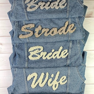 May include: Five denim jackets with pearl and rhinestone embellishments spelling out "Bride", "Bride", "Wife", "Mrs", and "Strode".