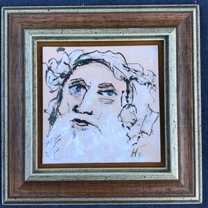 May include: A framed black and white drawing of a man with a beard and long hair. The drawing is on a light pink background and is signed "Hq" in the bottom right corner.