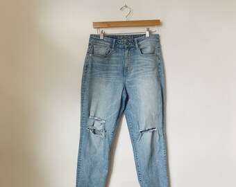 May include: Light blue denim jeans with distressed details and a cuffed hem. The jeans have the word "ARIZONA" on the back waistband.