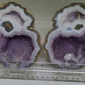 May include: Two halves of a geode with purple amethyst crystals inside. The geode is about 6 inches wide.