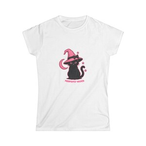 May include: A white short-sleeved t-shirt featuring a graphic of a black cat wearing a pink witch hat with a bow. The cat is surrounded by a pink crescent moon and small stars. Below the cat, the text reads PURRFECTLY WICKED in pink letters.