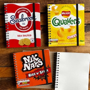 Puede incluir: Tres cuadernos de espiral con dise&ntilde;os de diferentes marcas de patatas fritas. El primer cuaderno es rojo y blanco con el logotipo de la marca Seabrook y el texto "Sea Salted". El segundo cuaderno es amarillo con el logotipo de la marca Walkers y el texto "Quaver's Cheese". El tercer cuaderno es naranja con el logotipo de la marca Nik Naks y el texto "Nice 'n' Spicy".