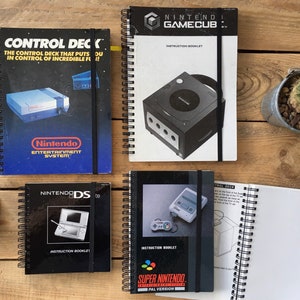 May include: Four spiral bound instruction manuals for video game consoles. The manuals are for the Nintendo GameCube, Nintendo DS, Super Nintendo, and the Nintendo Entertainment System. The manuals are all black and white with color accents.