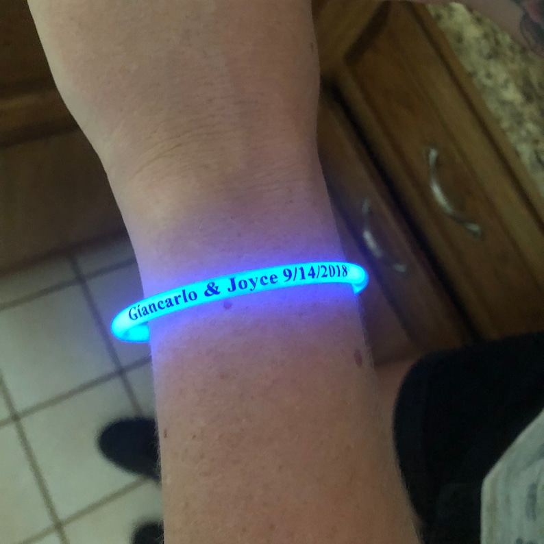 May include: A blue glow-in-the-dark bracelet with the text "Giancarlo & Joyce 9/14/2018" printed on it.