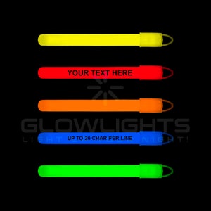 Op de afbeelding: Vijf glowsticks in verschillende kleuren: geel, rood, oranje, blauw en groen. Elke glowstick heeft een lus aan het uiteinde en is gelabeld met de tekst "YOUR TEXT HERE" of "UP TO 20 CHAR PER LINE".
