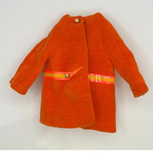 May include: An orange coat with long sleeves and a round collar. The coat features a yellow and orange ribbon detail around the waist and gold-colored buttons. The coat is made of a soft, textured material.