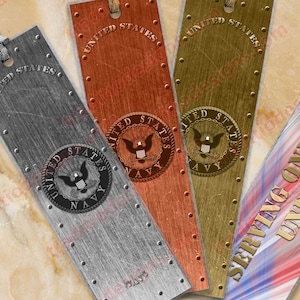 Puede incluir: Cuatro marcapáginas de metal con un aspecto desgastado. Cada marcapáginas presenta las palabras "United States Navy" y un sello con un águila. El cuarto marcapáginas tiene un fondo rojo, blanco y azul con las palabras "Serving One Nation Under God".