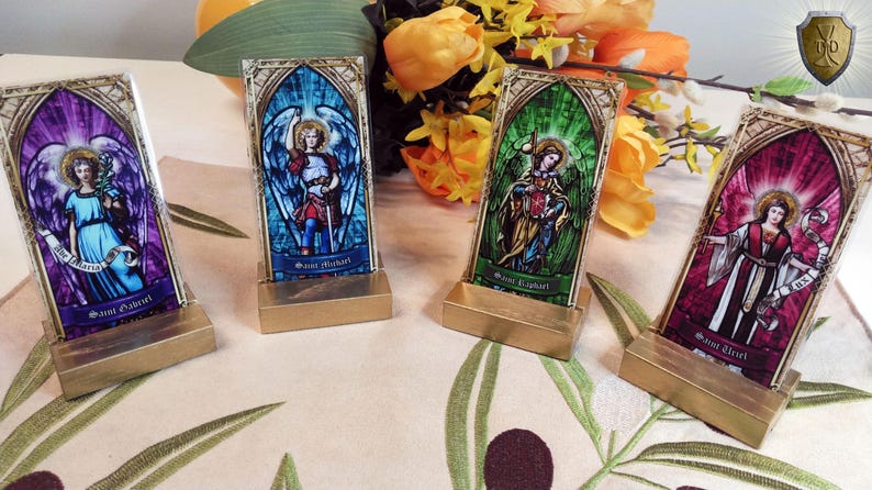 May include: Four small stained glass religious icons on gold stands. The icons feature images of angels with names "Saint Michael", "Saint Gabriel", "Saint Raphael", and "Saint Uriel".