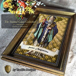 May include: A framed print titled The Stained Glass Collection featuring a depiction of Saint Augustine in blue and white robes, holding a heart and a staff. The background has a gold starburst pattern, and a banner reads Saint Augustine.