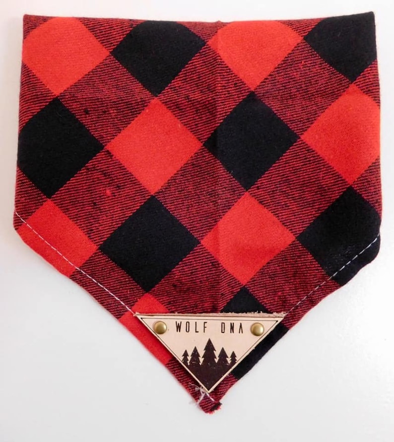 May include: Red and black checked bandana with a triangular leather patch that says "Wolf DNA" and has a silhouette of pine trees.
