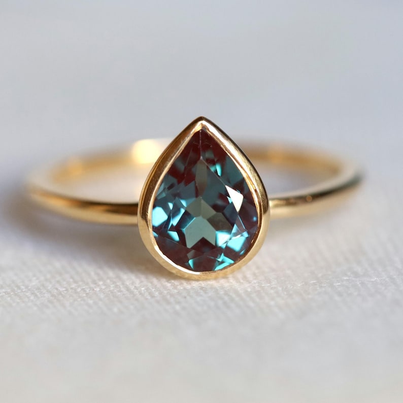 Pear cut Chatham Alexandrite engagement ring in solid gold. Color-changing Alexandrite stone on a basic ring.