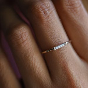 Anel minimalista com diamantes em lapidação baguete: aliança delicada para noivado e casamento.