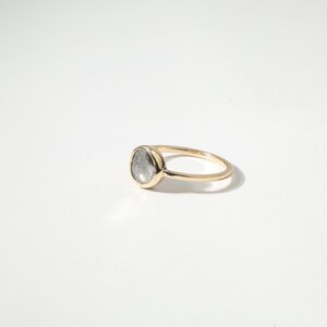 A gold ring with a large oval-shaped gemstone, possibly a diamond, set in the center of the band.