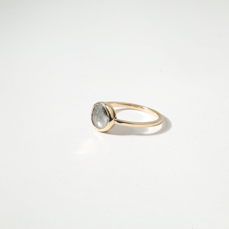 A gold ring with a large oval-shaped gemstone, possibly a diamond, set in the center of the band.