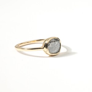 A gold ring with a large, oval-shaped gray stone set in the center.
