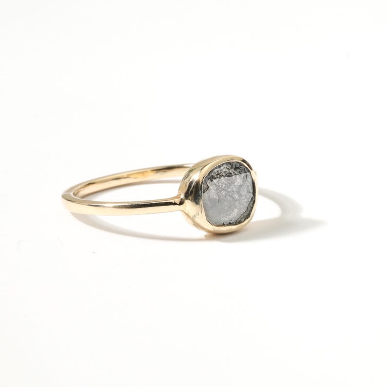 A gold ring with a large, oval-shaped gray stone set in the center.