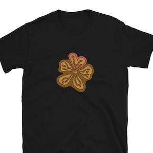 Può includere: Maglietta nera con una grafica di un fiore marrone con un cuore rosa al centro.