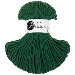 May include: A skein of dark forest green cord yarn wrapped with a white paper label featuring the black text Bobbiny. The cord is arranged in a fan-like shape, secured in the centre by the branded band, showcasing a smooth, braided texture.