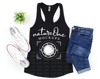 May include: A black racerback tank top featuring the white text natureOne MOCKUPS above a white circular camera lens graphic. The tank top is displayed alongside a pair of white canvas sneakers and blue denim jeans with a small green plant.