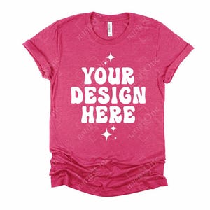 May include: A heathered fuchsia short-sleeve t-shirt with a crew neckline. The center of the shirt features the white text "YOUR DESIGN HERE" in a bold, rounded font, flanked by small four-pointed star icons above and below the text.