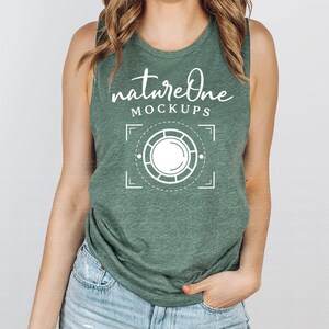 Peut inclure: Un débardeur vert avec le texte "natureOne MOCKUPS" en écriture blanche. En dessous du texte se trouve un graphique blanc d'un objectif d'appareil photo. Le débardeur est fait d'un tissu doux et chiné.