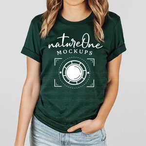 Puede incluir: Una camiseta verde oscuro con el texto "natureone MOCKUPS" y un gráfico blanco de una lente de cámara dentro de un marco cuadrado.