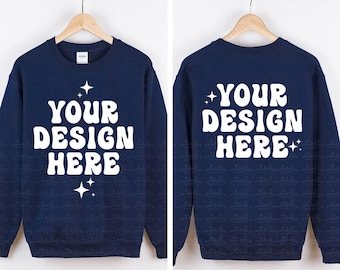 May include: A navy blue crewneck sweatshirt featuring the white text YOUR DESIGN HERE in a wavy font, accented by four-pointed star icons. The image displays both the front and back views of the garment, each hanging on a wooden hanger.