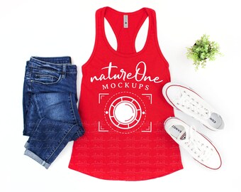 May include: A bright red racerback tank top featuring the white text natureOne MOCKUPS above a circular graphic design, paired with dark blue denim jeans and a pair of white canvas sneakers with white laces and rubber soles.