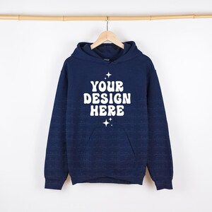 May include: A navy blue hooded sweatshirt with a white pocket and the text "YOUR DESIGN HERE" in a retro font.