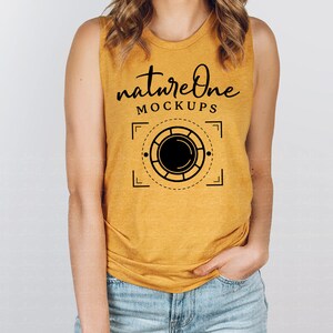 Peut inclure: Un débardeur jaune moutarde sans manches avec le texte "natureOne MOCKUPS" et un graphique noir et blanc d'un objectif d'appareil photo.