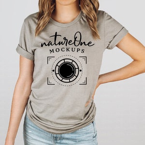 May include: A gray t-shirt with a black graphic design that says "nature one" and "MOCKUPS" with a stylized camera lens graphic.