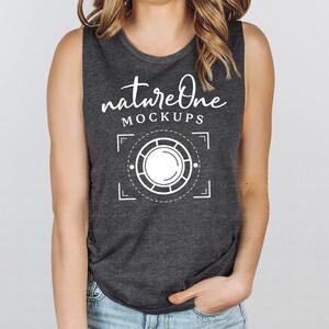 Peut inclure: Un débardeur gris foncé avec le texte "natureone MOCKUPS" et un graphique blanc d'un objectif d'appareil photo avec un cercle au centre.