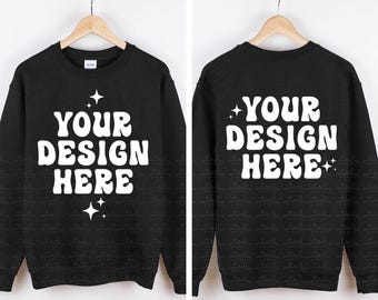 May include: A black crewneck sweatshirt featuring white text that reads YOUR DESIGN HERE in a bold, wavy font, accented by small four-pointed star graphics. The image displays both the front and back views of the garment on wooden hangers.