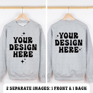 Könnte beinhalten: Ein hellgraues Sweatshirt mit Rundhalsausschnitt und dem schwarzen Text "YOUR DESIGN HERE" in einer wellenförmigen Schriftart, akzentuiert durch kleine vierzackige Sternsymbole. Das Bild zeigt die Vorder- und Rückseite auf einem Holzkleiderbügel.