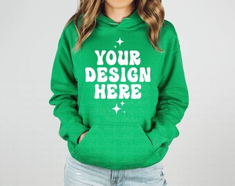 May include: A bright green hooded sweatshirt featuring a front kangaroo pocket and white text printed on the chest that reads YOUR DESIGN HERE, accented by small four-pointed star graphics above and below the text in a bold, rounded font.
