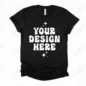 May include: A black short-sleeved t-shirt featuring the white text "YOUR DESIGN HERE" in a bold, rounded font. The design is centered on the chest and is accented by small four-pointed star icons positioned above and below the text.