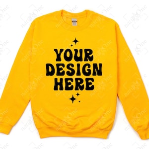 Può includere: Una felpa girocollo giallo brillante con il testo nero "YOUR DESIGN HERE" stampato in un carattere grassetto e ondulato al centro del petto. Il testo è accentuato da piccole icone a forma di stella a quattro punte sopra e sotto.