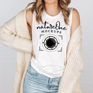 Peut inclure: Un débardeur blanc sans manches avec le texte "natureone MOCKUPS" et un motif graphique noir et blanc d'un objectif d'appareil photo.
