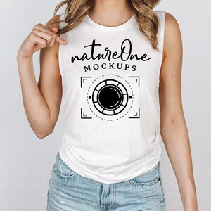 Peut inclure: Un t-shirt blanc sans manches avec le texte "natureone MOCKUPS" et un graphique noir et blanc d'un objectif d'appareil photo.