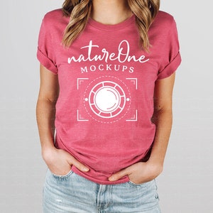 May include: A heathered dark pink short-sleeve t-shirt featuring white text that reads natureOne MOCKUPS above a white graphic of a circular camera lens frame with corner brackets and dashed lines centered on the chest area of the garment.