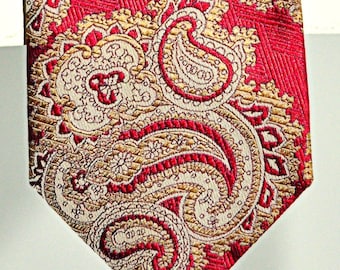 May include: A red and gold paisley patterned tie. The tie has a pointed tip and a classic design.